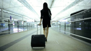 a woman walking through an airport with a travel bag