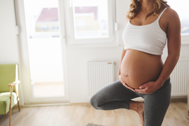 A pregnant woman practices yoga in her home