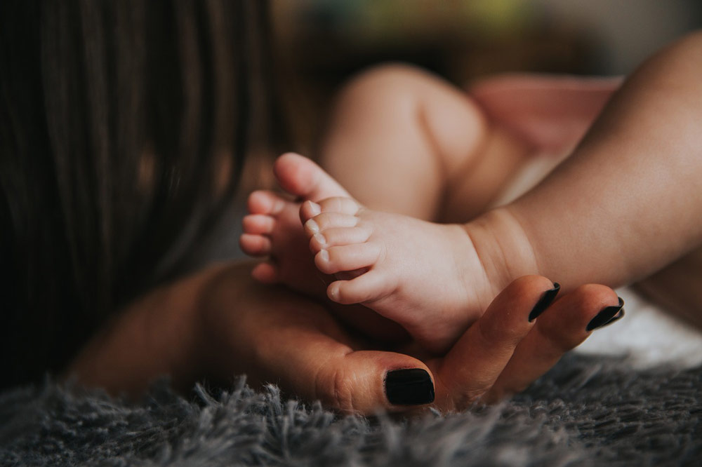 mother’s hands holding baby’s feet