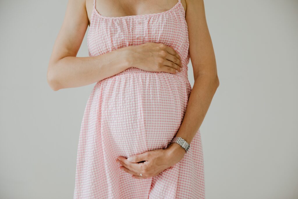 Photograph of a woman surrogate holding her pregnant belly