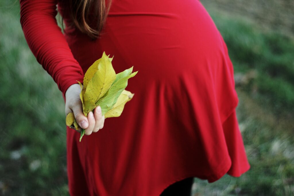 Photo of a pregnant woman holding a handful of leaves