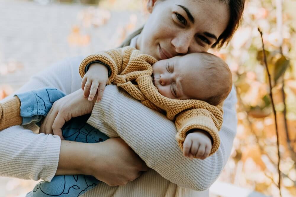 A woman holds a sleeping infant