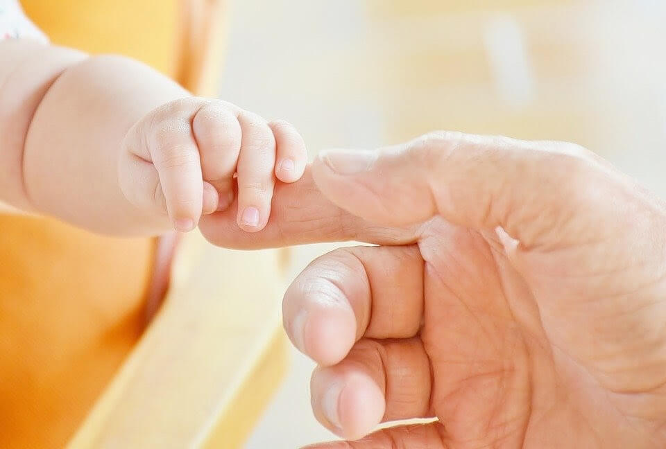 Baby holding parent finger