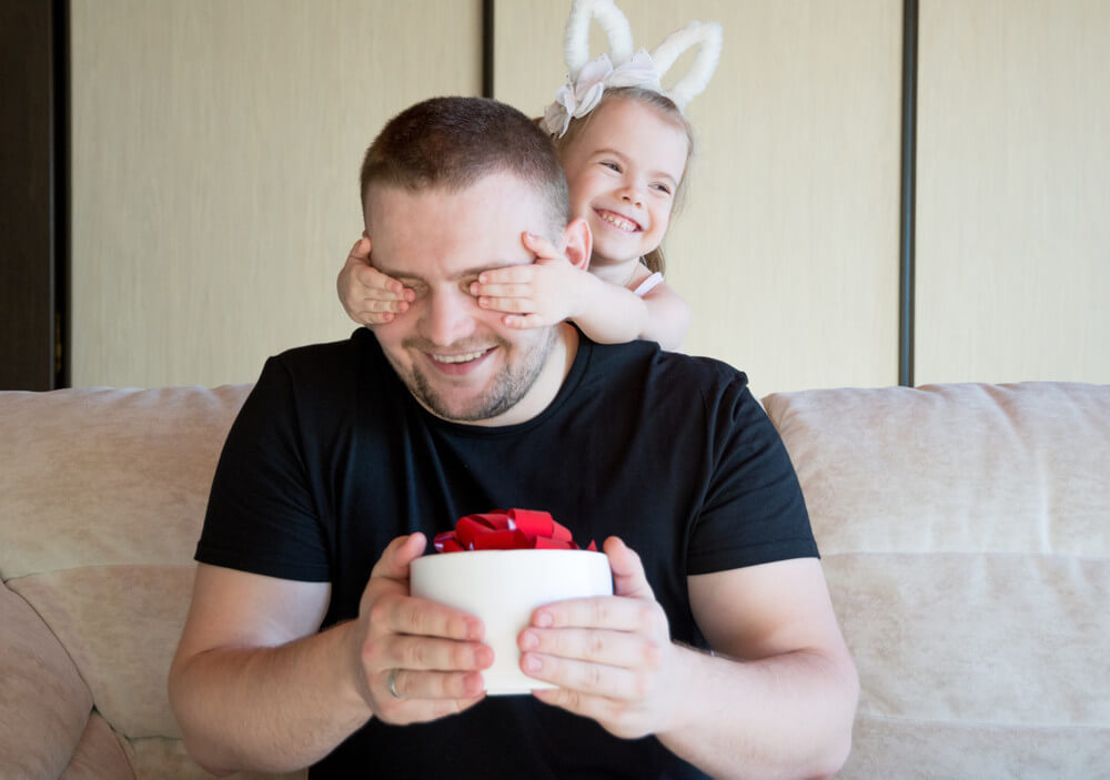 a daughter giving her dad a gift with a red bow