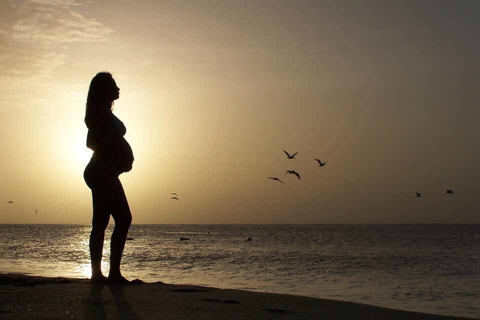 pregnant woman on the beach during sunset