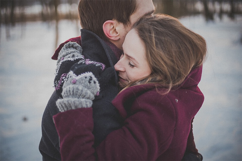 A man hugging a woman outside in the wintertime.
