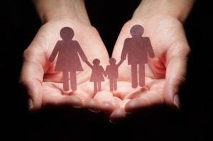 Photo of hands holding a paper cut-out of a family
