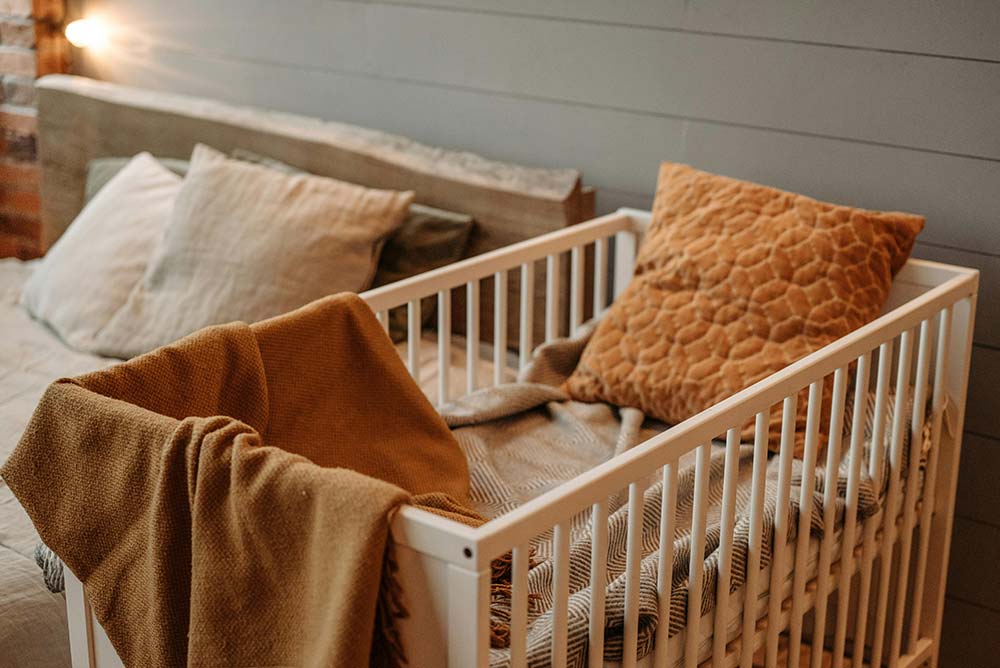 A baby’s crib with a cozy pillow and blanket ready for the baby to come.