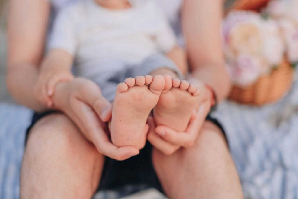 A parent holding a baby’s feet in their hands